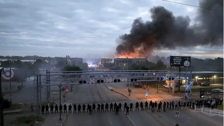 Agentes de Policía congregados a lo largo de una calle en Mineápolis (EE.UU.) con incendios activos tras una noche de disturbios, el 29 de mayo de 2020.