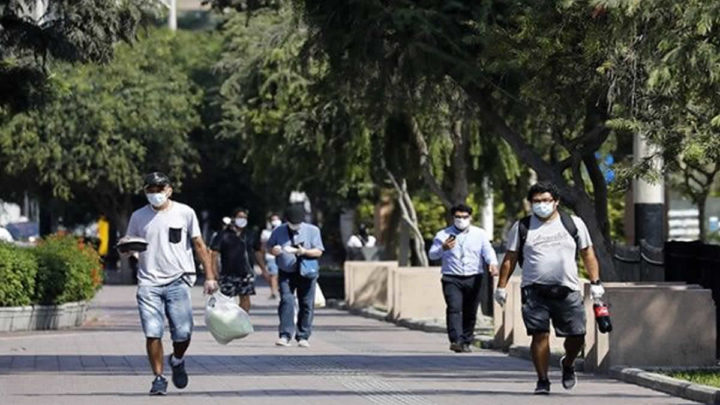 Personas con mascarillas caminando por un parque