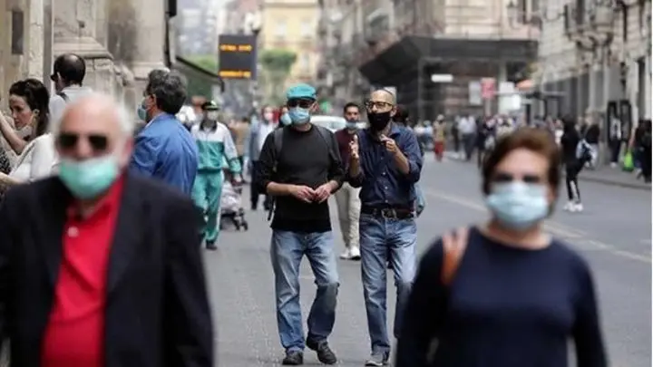 Personas con mascarillas caminando por una avenida