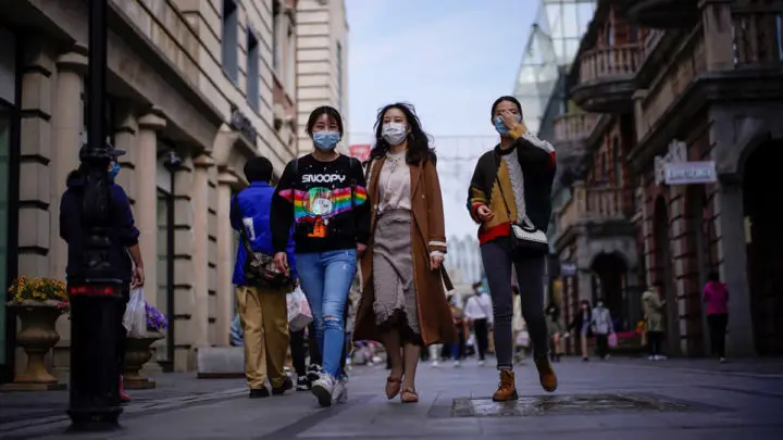 Personas con máscaras en una zona comercial después del levantamiento de las restricciones en Wuhan