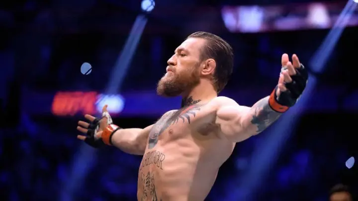 El luchador irlandés Conor McGregor alza los brazos en señal de triunfo.