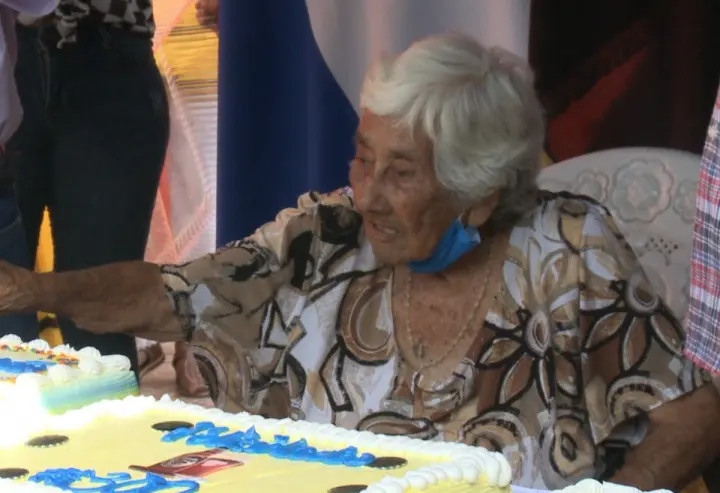 Beneficiada con vivienda digna corta un pastel en celebración.