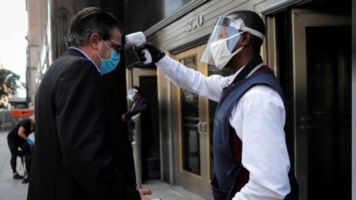 Un empleado toma la temperatura a un hombre frente al Empire State Building en el centro de Manhattan, en la ciudad de Nueva York, Estados Unidos.