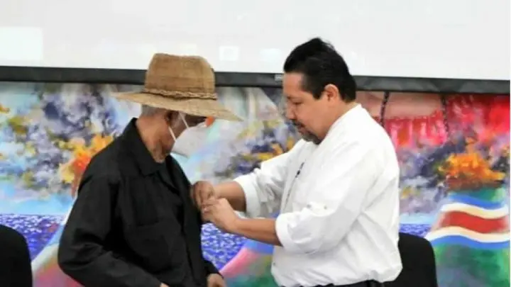 Salvador Vanegas coloca medalla al profesor Orlando Pineda.