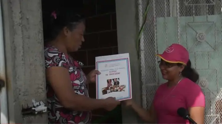 Mujer recibiendo título de propiedad.