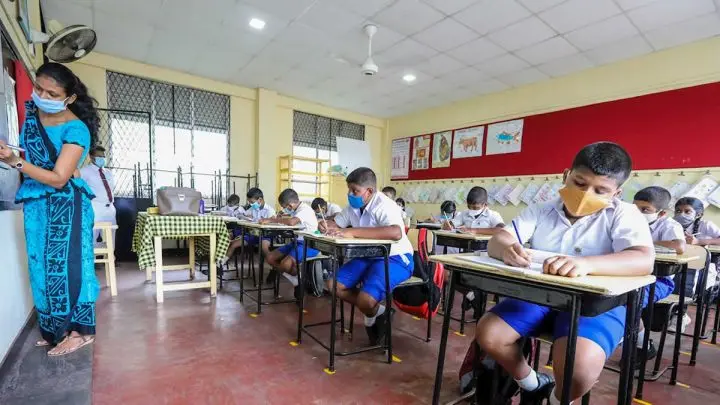 Maestra y alumnos usan mascarilla como medida sanitaria ante el COVID-19 en un aula de clase