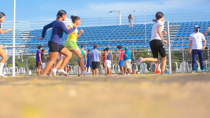 Niños corriendo en una cancha de voleibol playa.