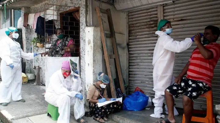 Trabajadores de salud examinan a los residentes de un barrio pobre en Bombay, India.