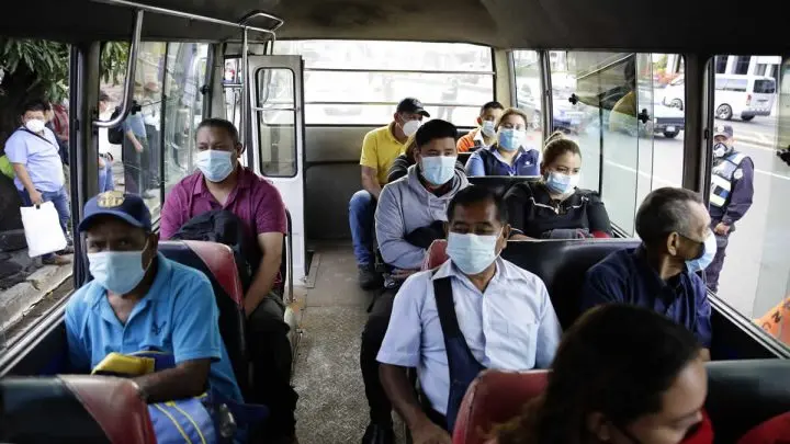 Salvadoreños a borda de un auto bus usando mascarilla como protección ante el COVID-19