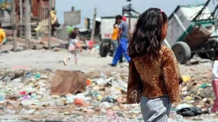 Niña caminando de espaldas en un basurero.