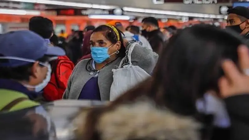 Señora con mascarilla en medio de multitud en América Latina.