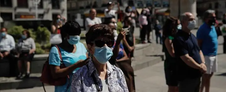 Personas con mascarilla en un avenida en España.