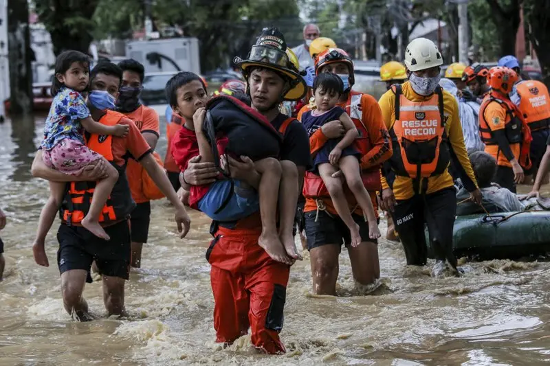 Bomberos rescatando niños tras el paso de tifón Vamco en Filipinas.